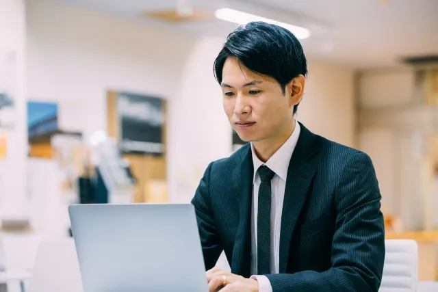 ノートパソコンを操作するスーツを着た男性