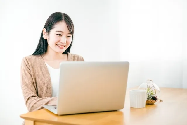 机で白いノートパソコンを操作している女性