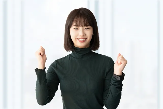 笑顔でガッツポーズを両手でする黒い服を着た女性