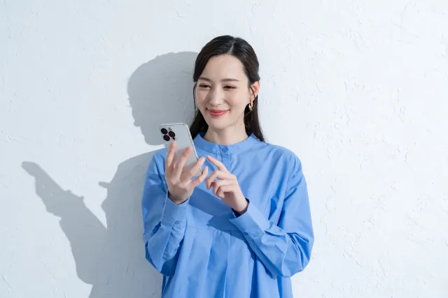 スマホを操作する笑顔の青い服を着た女性