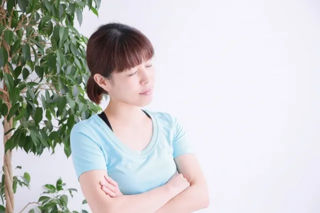 目をつぶって腕組みをしながら考えている女性