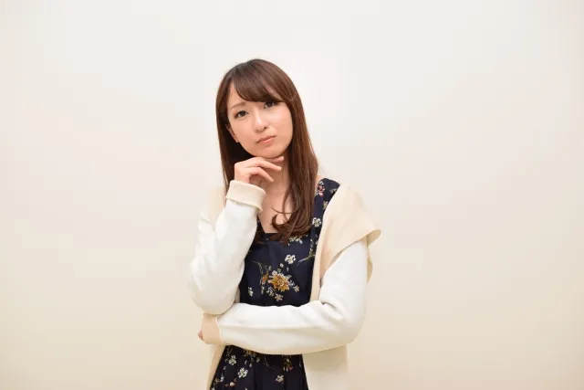 右手を顎に当てて考え事をしている女性