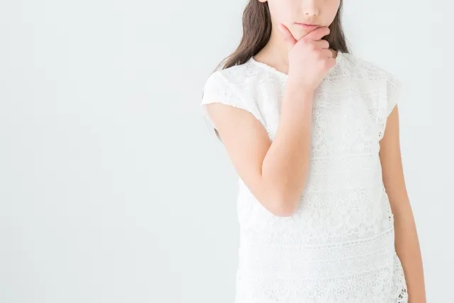 右手で顎を掴んで考えている白い服の女性