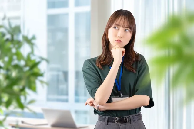 オフィスで左手で抑えて右手で頬杖して考えている女性