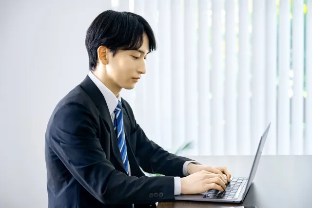 スーツ姿でノートパソコンを操作する男性