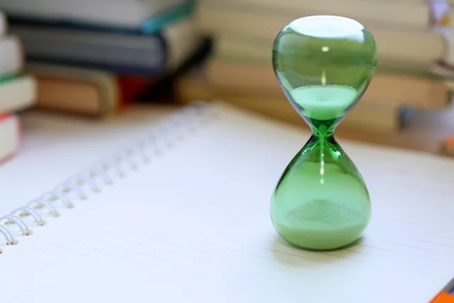 ノートの上に置かれた緑色の半透明の砂時計