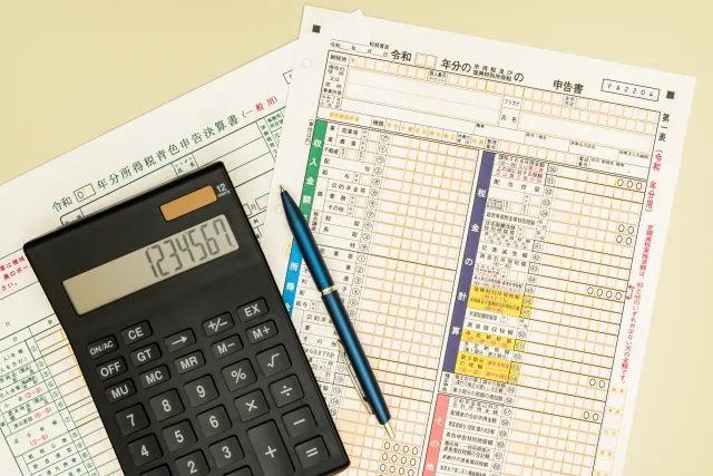 確定申告書の上に電卓とボールペンが置かれている